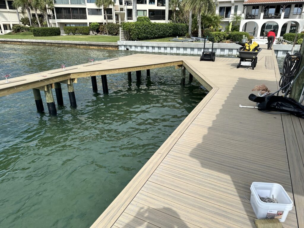 New composite decking laid over a dock frame with tools and fasteners still on the deck. Dock decking installation by Anderson Dock and Lift, Sarasota FL.