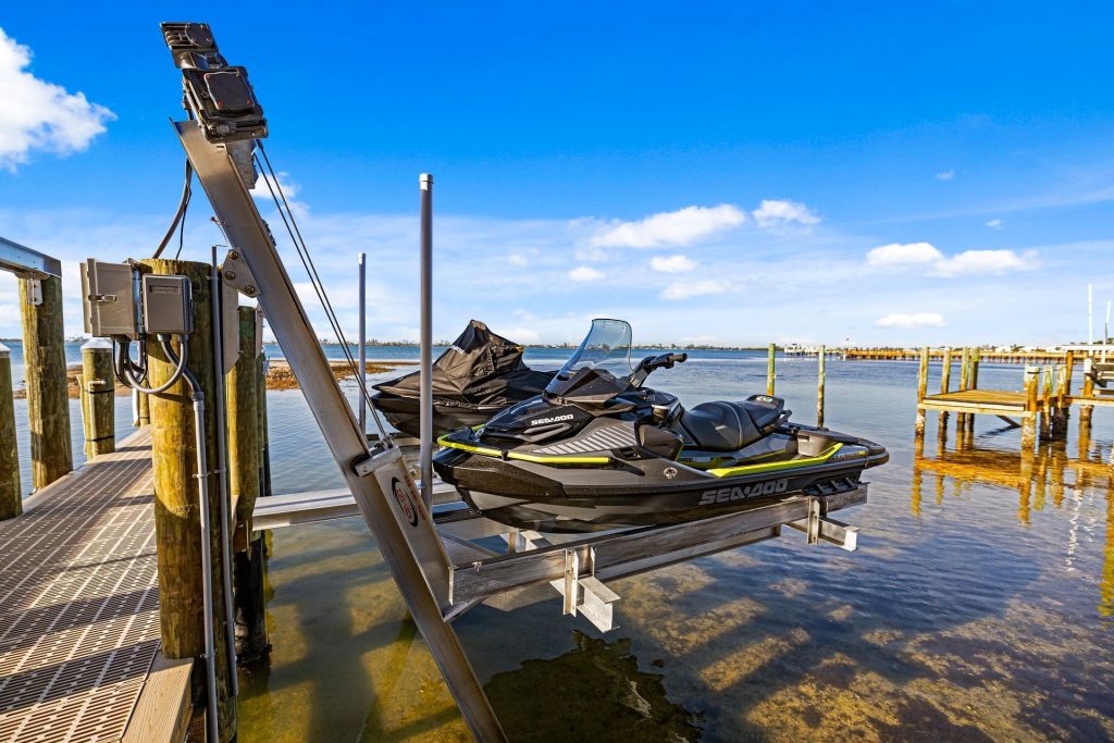 Two Sea-Doo personal watercraft on an aluminum jet ski lift beside a dock. Jet ski lift installation, Anderson Dock and Lift, Bradenton FL.