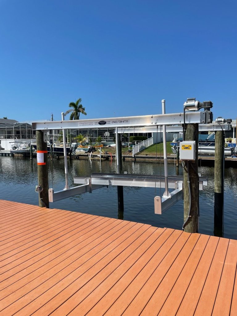 Boat lift on a wooden dock along a saltwater canal. Boat lift installation by Anderson Dock and Lift, Bradenton FL.
