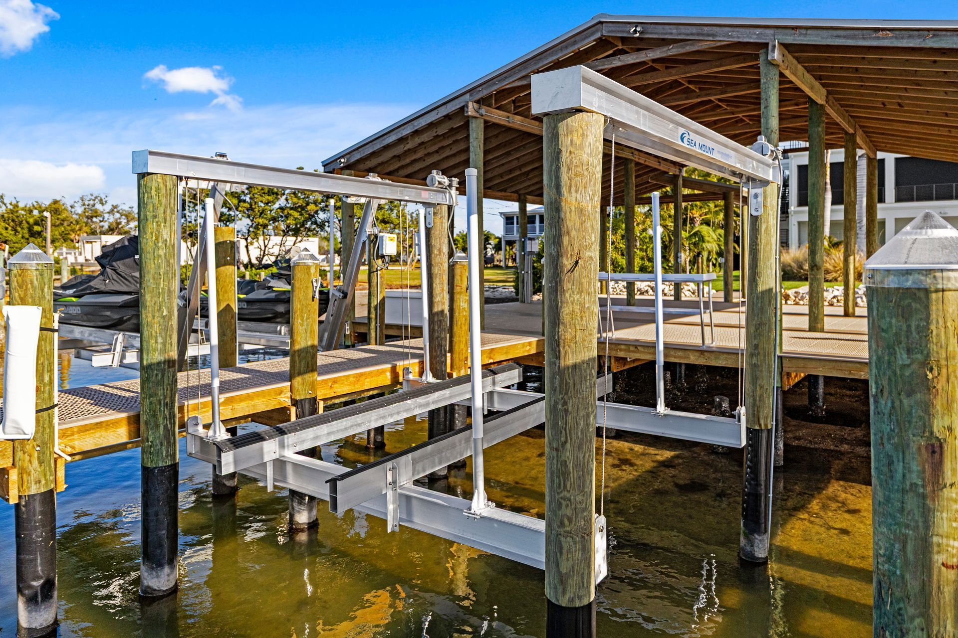 Boat lift on a dock with wooden posts, under a canopy. Boat lift installation by Anderson Dock and Lift, Manatee County FL.