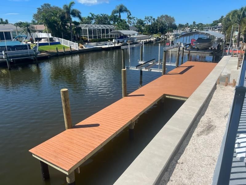Composite dock running alongside a new concrete seawall and cap on a canal. Seawall construction by Anderson Dock and Lift, Sarasota FL.