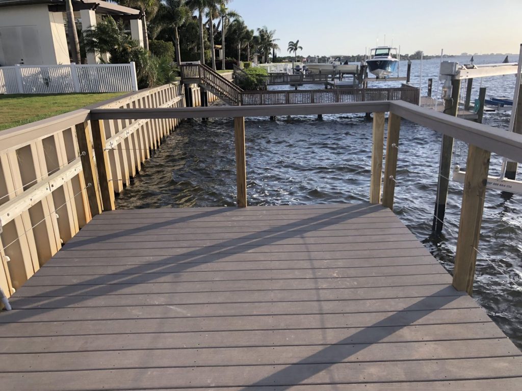 Wide composite dock walkway with wood railings and stairs up to the house. Custom dock construction by Anderson Dock and Lift, Tampa FL.