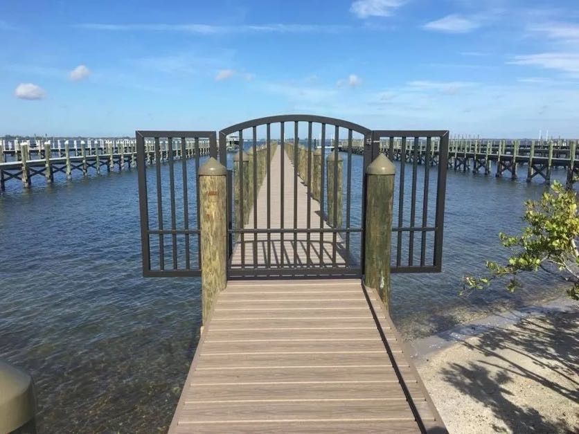 Dock walkway with a metal security gate set between capped pilings. Custom dock construction by Anderson Dock and Lift, St. Petersburg FL.