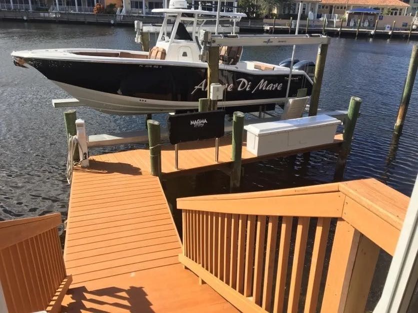 Black and white powerboat raised on a boat lift beside dock stairs. Boat lift installation, Anderson Dock and Lift, Bradenton FL.