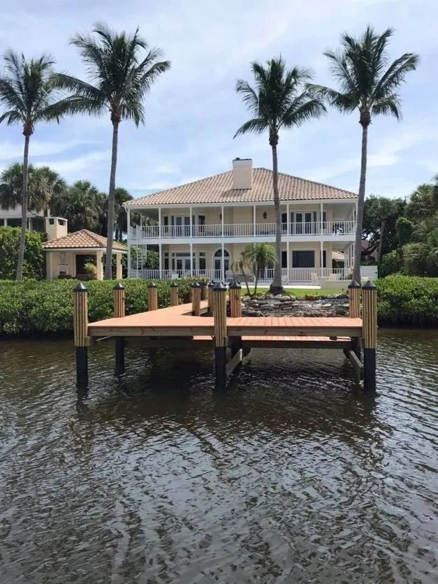 Composite dock and mooring pilings fronting a waterfront home. Dock builder Anderson Dock and Lift, Fort Myers FL.