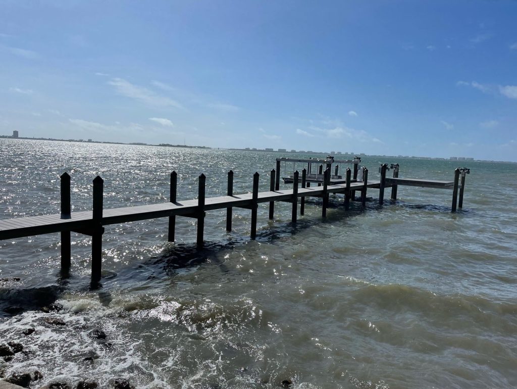 Wooden pier extending into open water under a clear sky. Pier construction by Anderson Dock and Lift, Sarasota County FL.