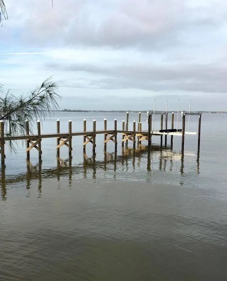 Dock with wood railings turning across shallow water. Dock builder Anderson Dock and Lift, Apollo Beach FL.