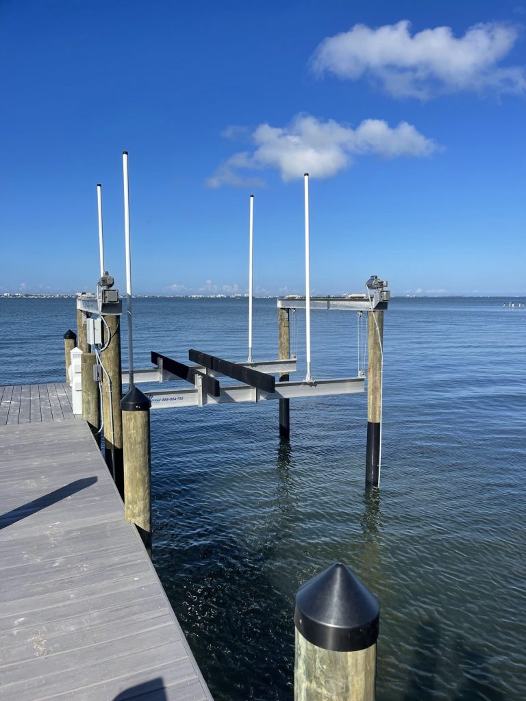 Dock and boat lift over calm water under a clear sky. Boat lift installation by Anderson Dock and Lift, Manatee County FL.