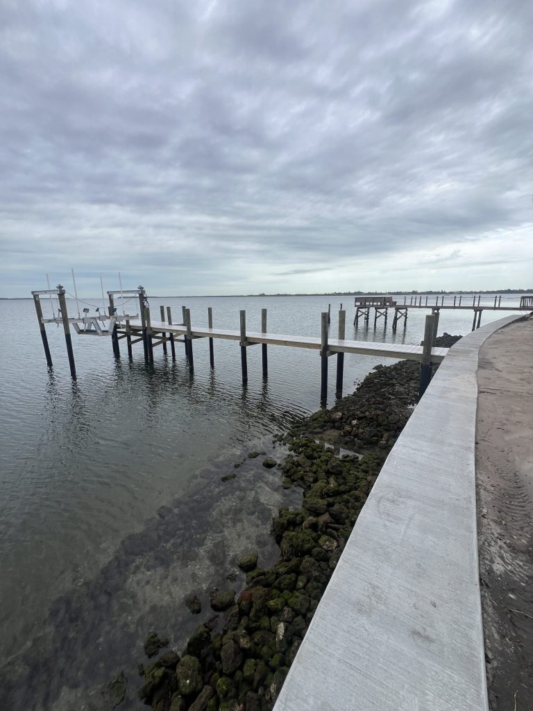 New concrete seawall with cap, walkway and rock rip rap at the toe. Seawall construction by Anderson Dock and Lift, Fort Myers FL.