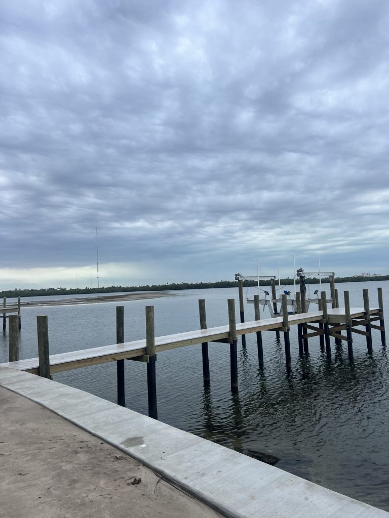 New concrete seawall and cap with a dock and boat lift beyond. Seawall contractor Anderson Dock and Lift, Fort Myers FL.