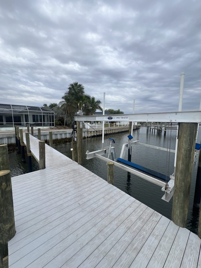 Wooden dock and boat lift over open water on an overcast day. Boat lift installation, Anderson Dock and Lift, Bradenton FL.
